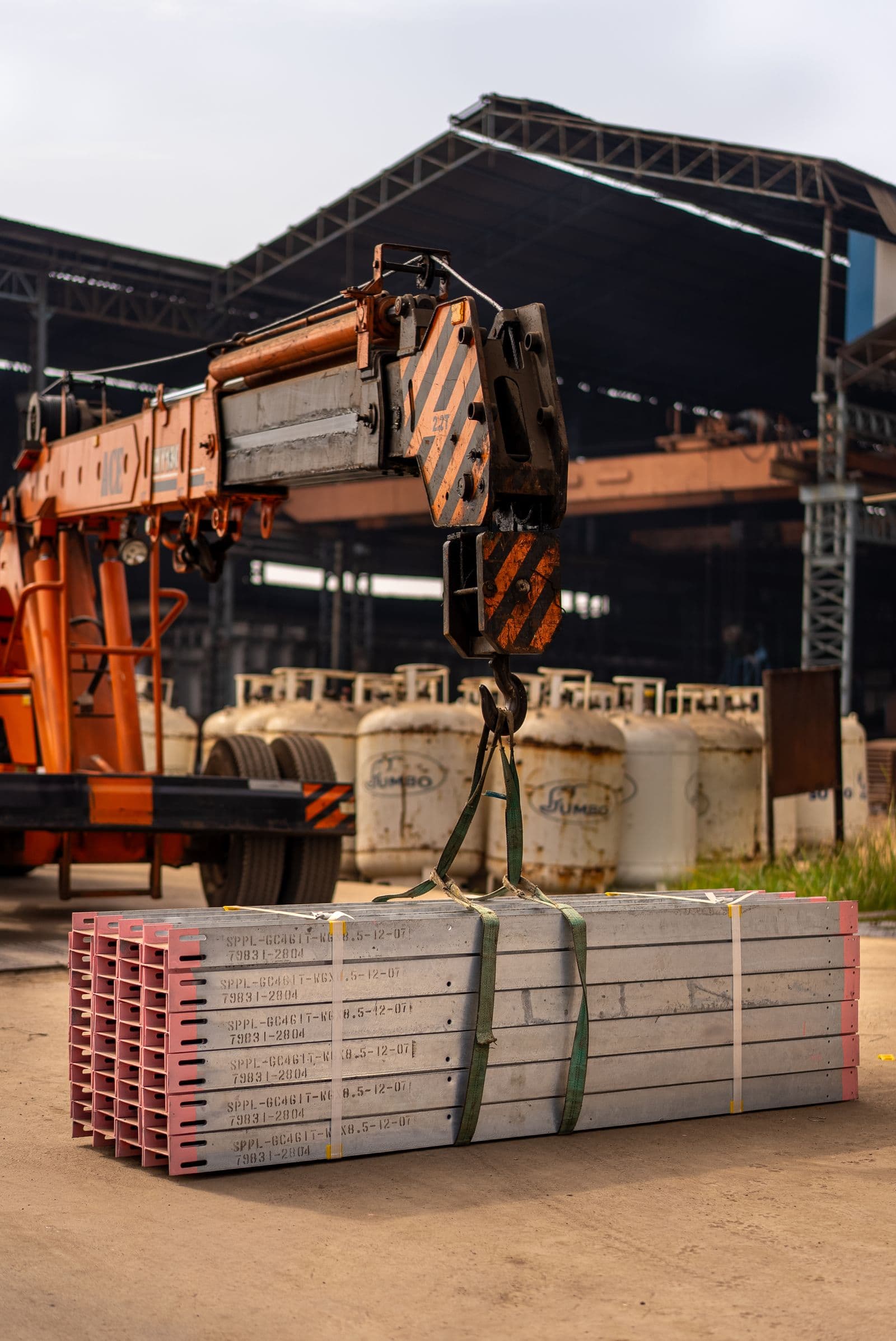 Industrial crane lifting metal beams in a heavy-duty facility
